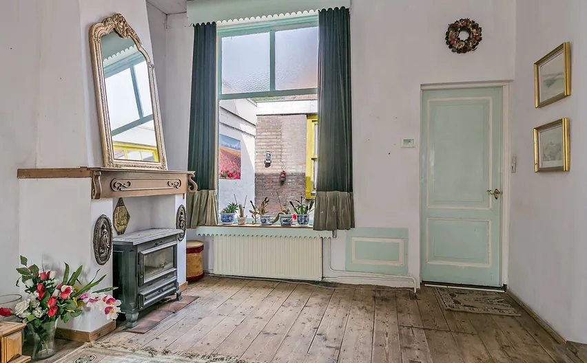 Gerenoveerde woonkamer in Hellevoetsluis met schouw, spiegel en brede houten vloerdelen